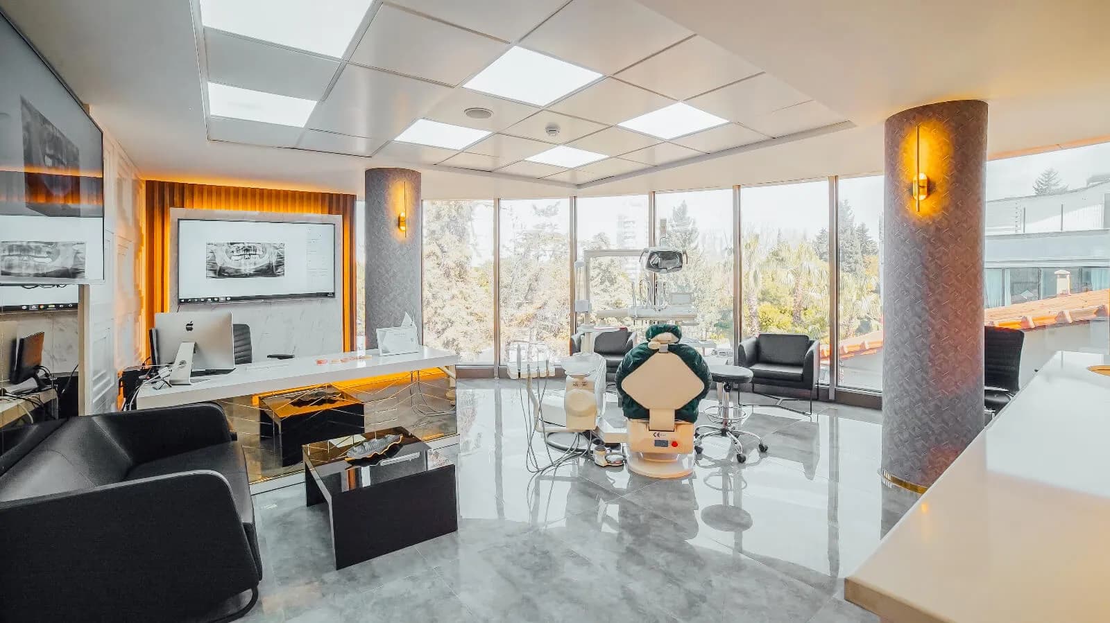 A corner treatment room at Ballıpınar Dental with floor-to-ceiling windows on two sides and X-rays on a wall-mounted screen