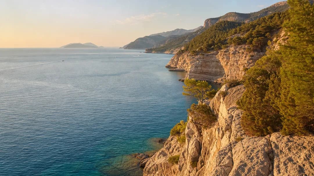 The Antalya coastline at golden hour, cliffs and turquoise sea with pine hills beyond
