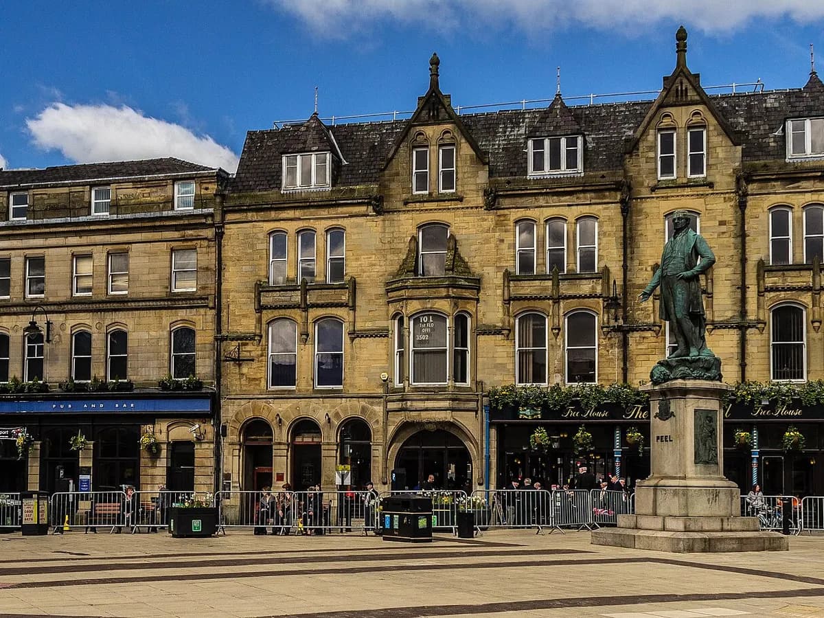 Bury: a covered market of stalls in a stone-built town with moorland rising beyond
