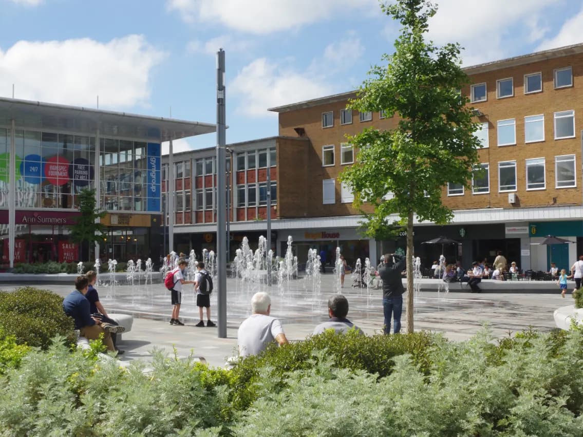 Crawley: a broad new-town boulevard of low modern shopfronts with an airliner low overhead