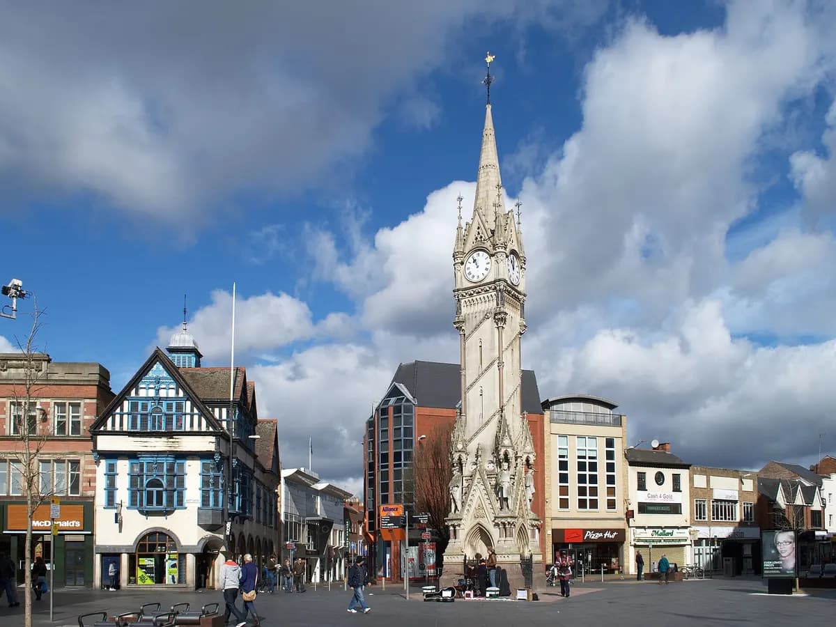 Leicester: an ornate stone clock tower where several streets meet, a cathedral spire behind
