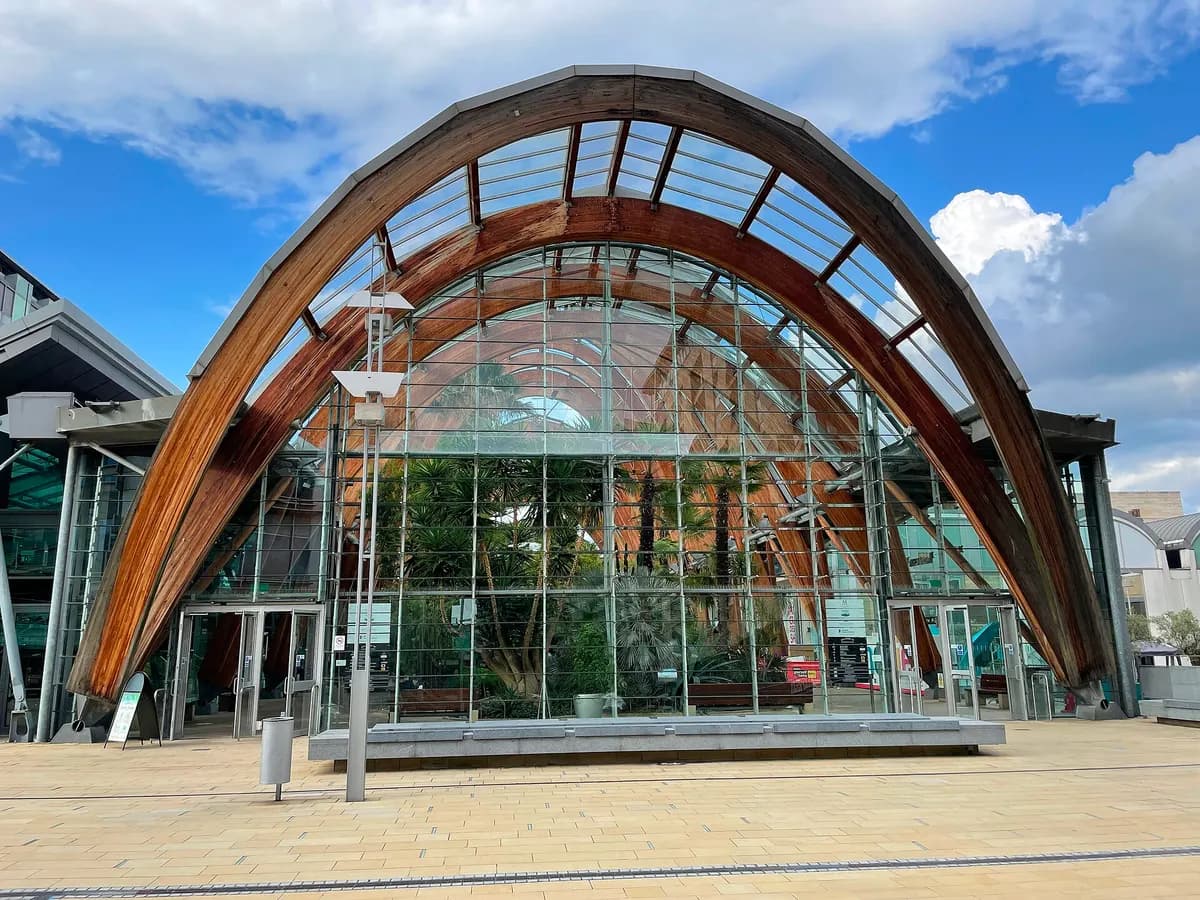 Sheffield: a curved glasshouse winter garden with wooded hills rising beyond the city