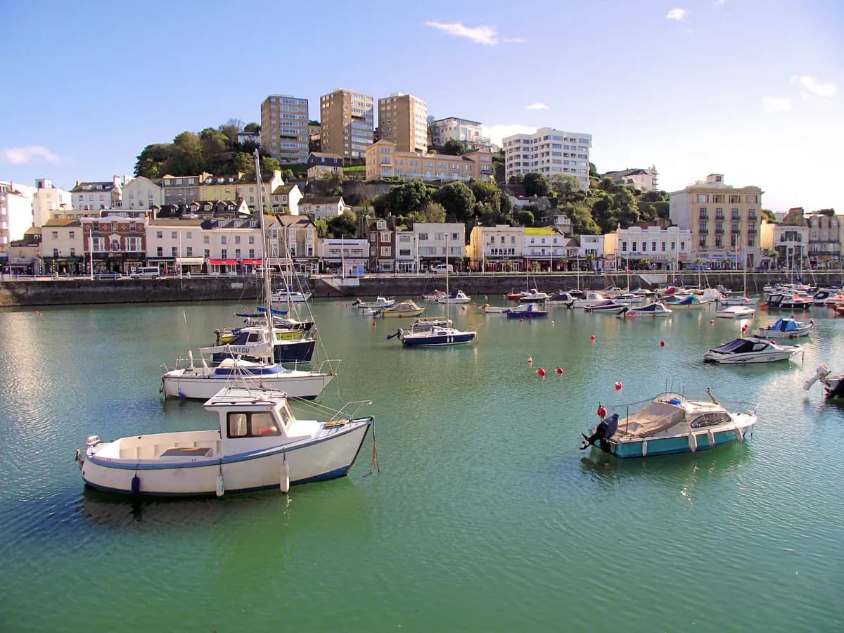 Torquay: a palm-lined harbour of white villas rising up green hills above blue water