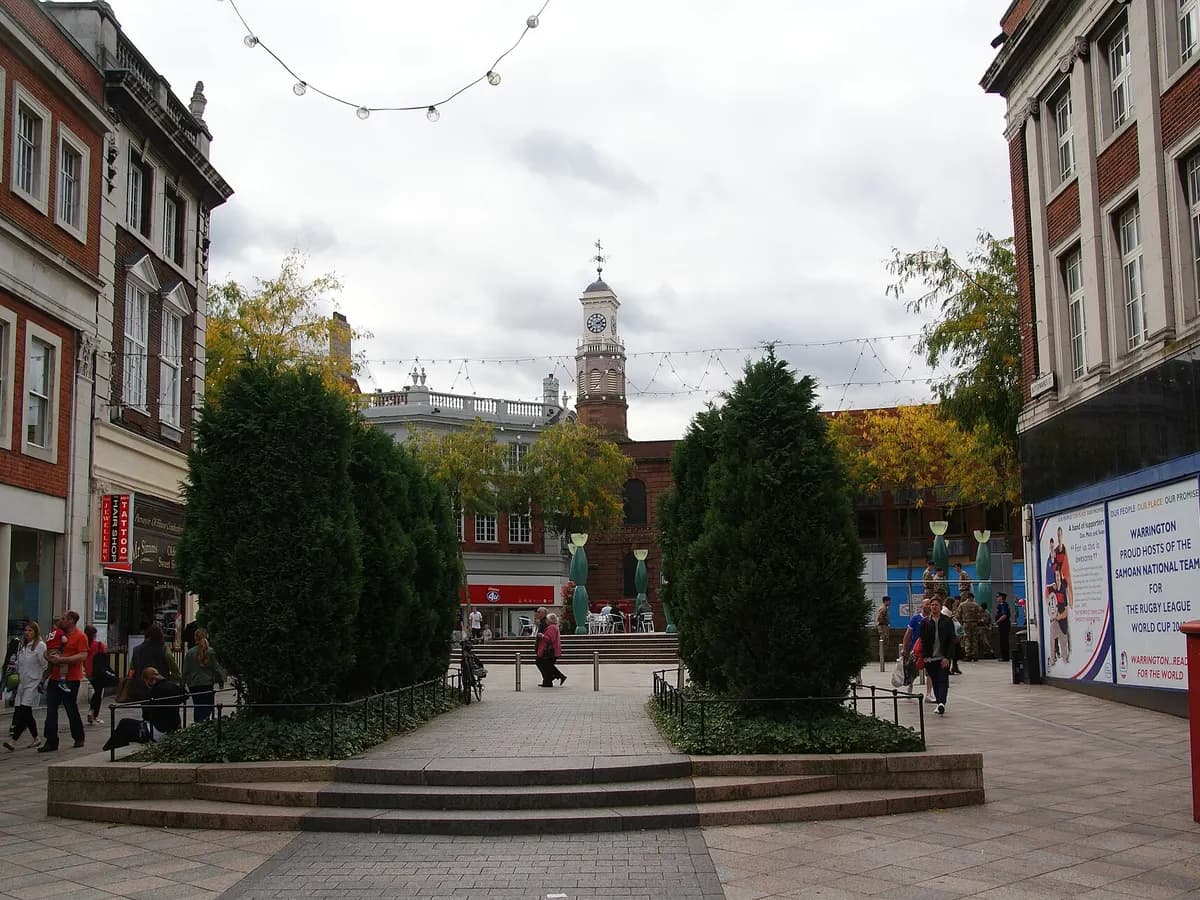 Warrington: a river bridge in a low red-brick town, tall transporter frames beyond