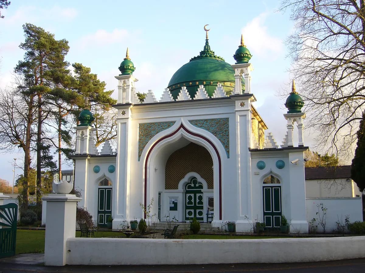 Woking: a small green-and-gold domed mosque with a minaret among trees, modern town blocks behind