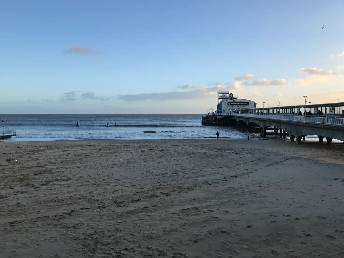 Bournemouth: a pier over a long sandy beach with pine-wooded valleys running down to it