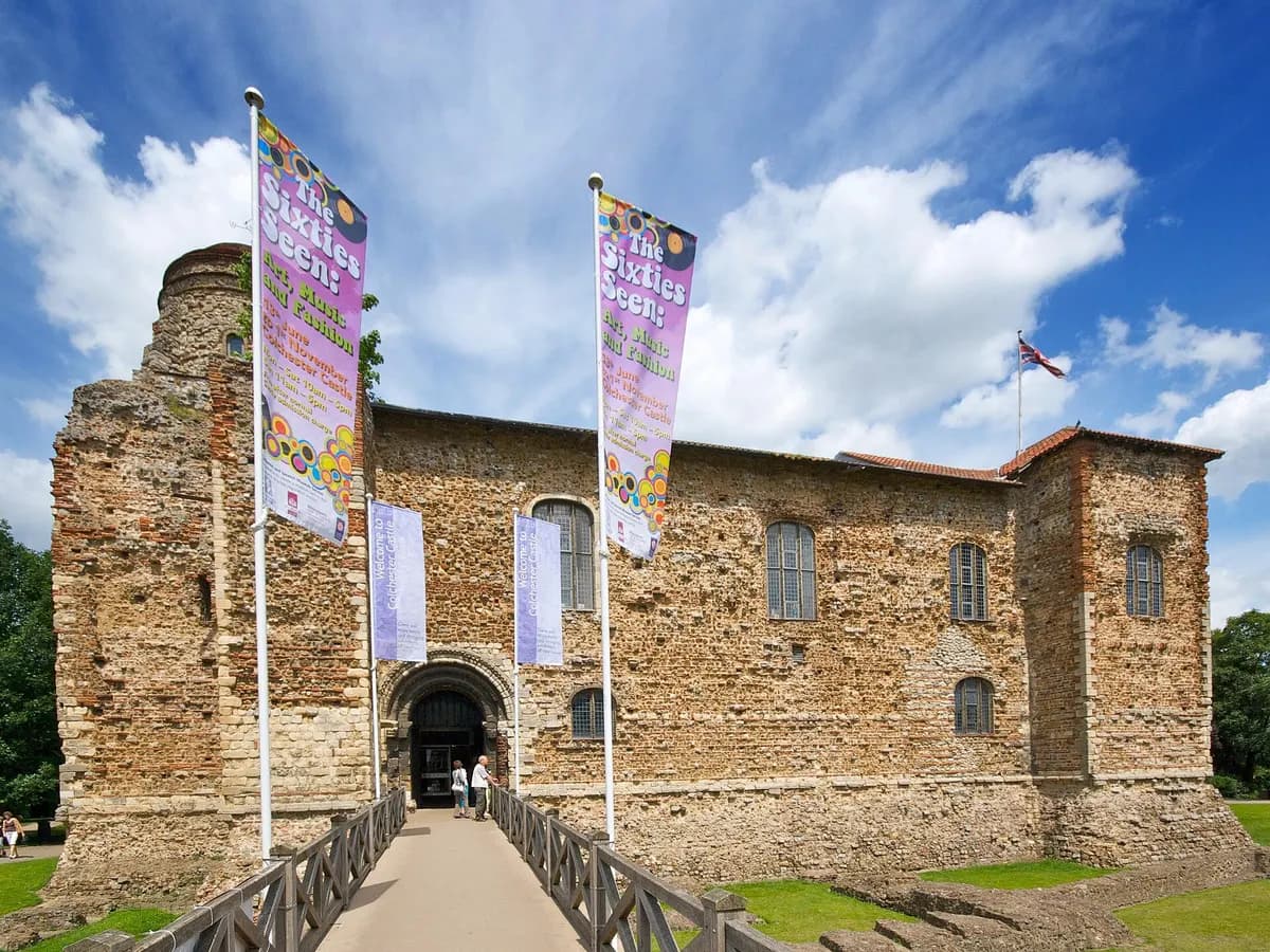 Colchester: a broad Norman castle keep among trees beside a stretch of Roman wall
