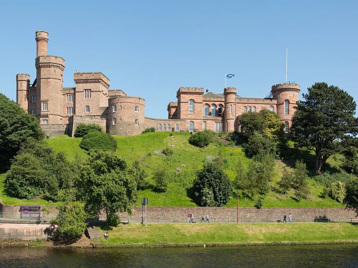 Inverness: a red sandstone castle above a river with a cathedral opposite and Highland hills behind