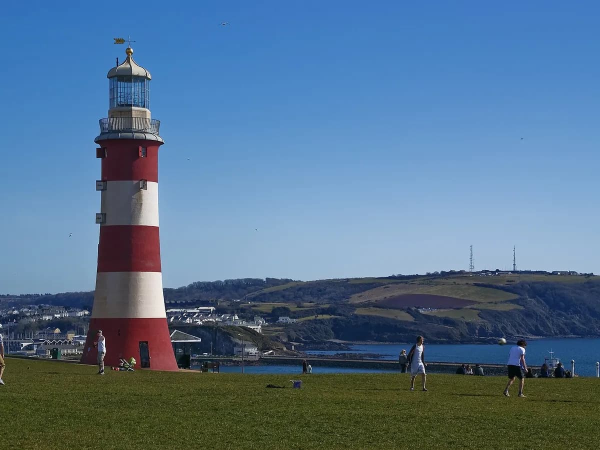 Plymouth: a red-and-white striped lighthouse tower on a grassy headland above the sound